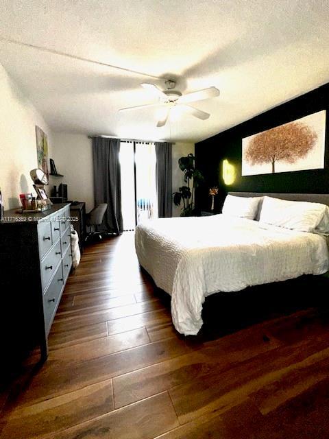 bedroom featuring ceiling fan, dark wood-type flooring, and a textured ceiling