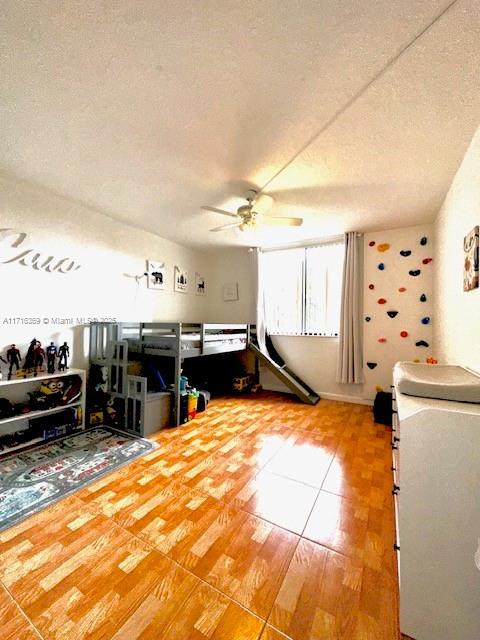 interior space with ceiling fan, a textured ceiling, and hardwood / wood-style flooring