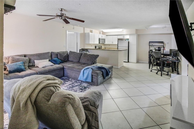 living room with ceiling fan, light tile patterned floors, and a textured ceiling