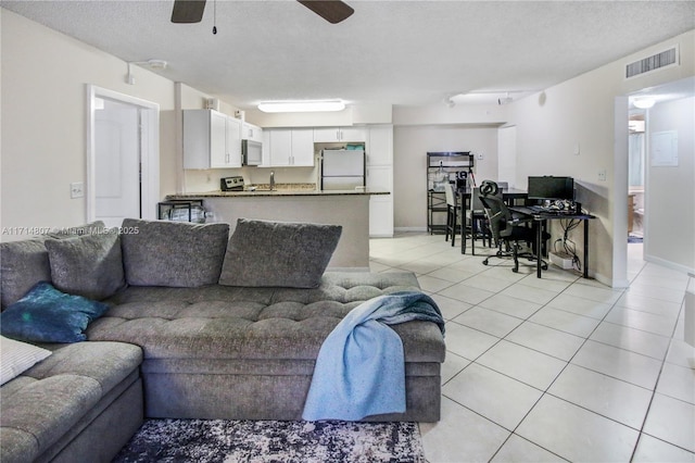 living room featuring ceiling fan, light tile patterned floors, and a textured ceiling