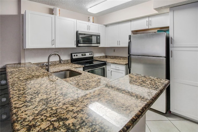 kitchen featuring kitchen peninsula, stainless steel appliances, white cabinetry, and sink