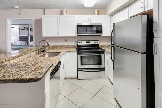 kitchen featuring white cabinetry, sink, stainless steel appliances, light stone counters, and kitchen peninsula