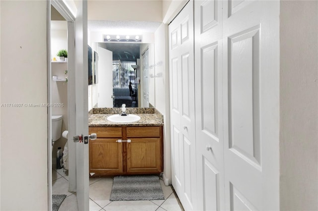 bathroom with toilet, a textured ceiling, vanity, and tile patterned floors