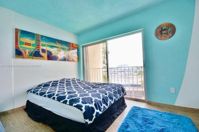 bedroom featuring hardwood / wood-style floors, a textured ceiling, and access to outside