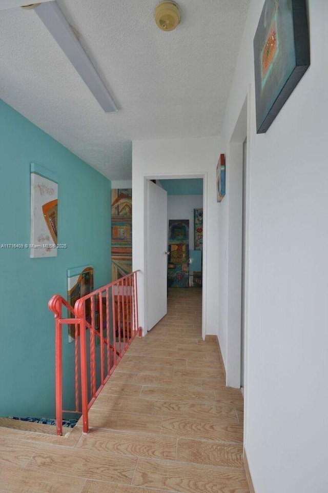 7801 NE 4th Ct Unit 317, Miami, FL 33138 - hall with an upstairs landing, wood finished floors, and a textured ceiling