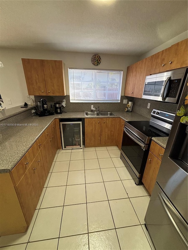 kitchen with light tile patterned floors, sink, backsplash, a textured ceiling, and stainless steel appliances