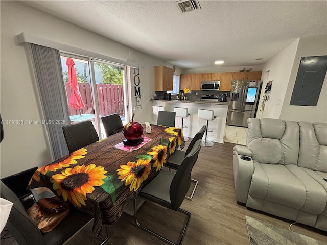 dining room with electric panel, dark hardwood / wood-style flooring, and a textured ceiling