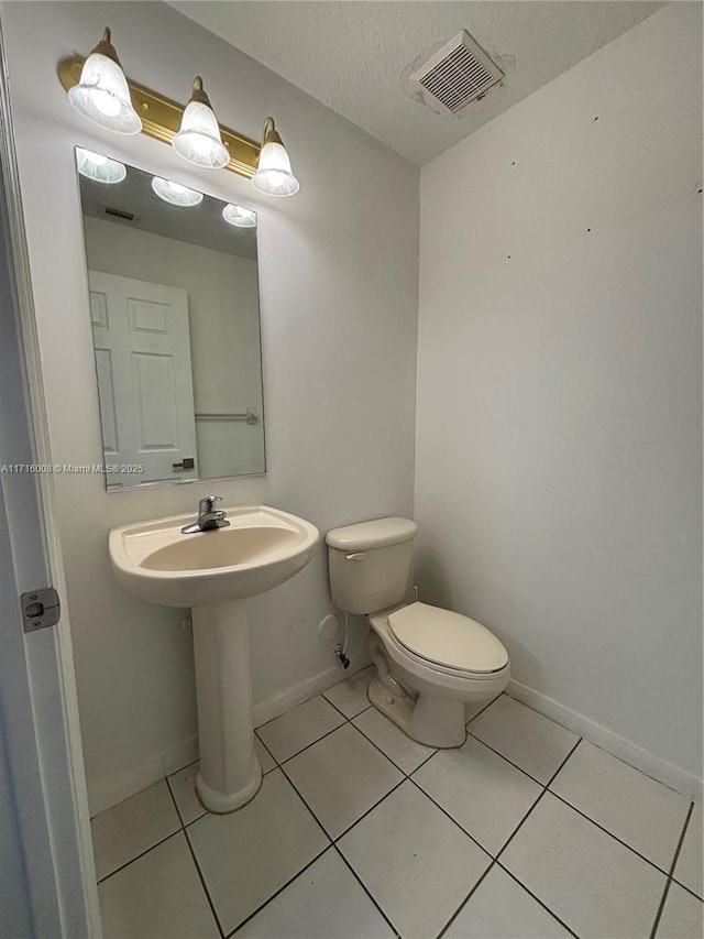 bathroom with tile patterned floors, toilet, and a textured ceiling