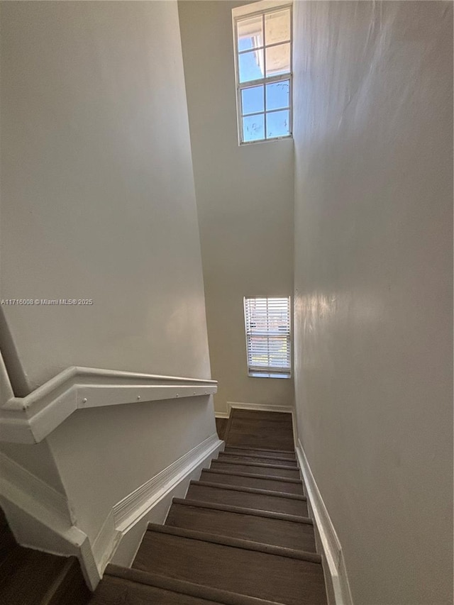 staircase featuring a towering ceiling and a wealth of natural light