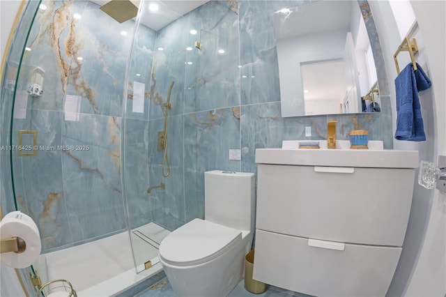 bathroom with vanity, toilet, tile walls, and a shower with shower door