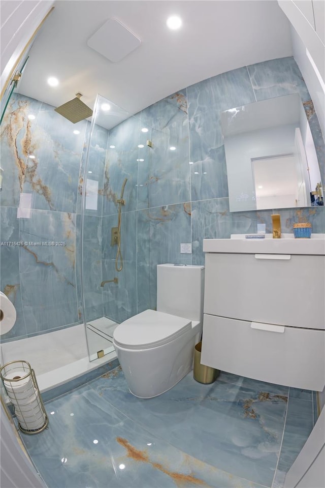 bathroom featuring tiled shower, vanity, tile walls, and toilet