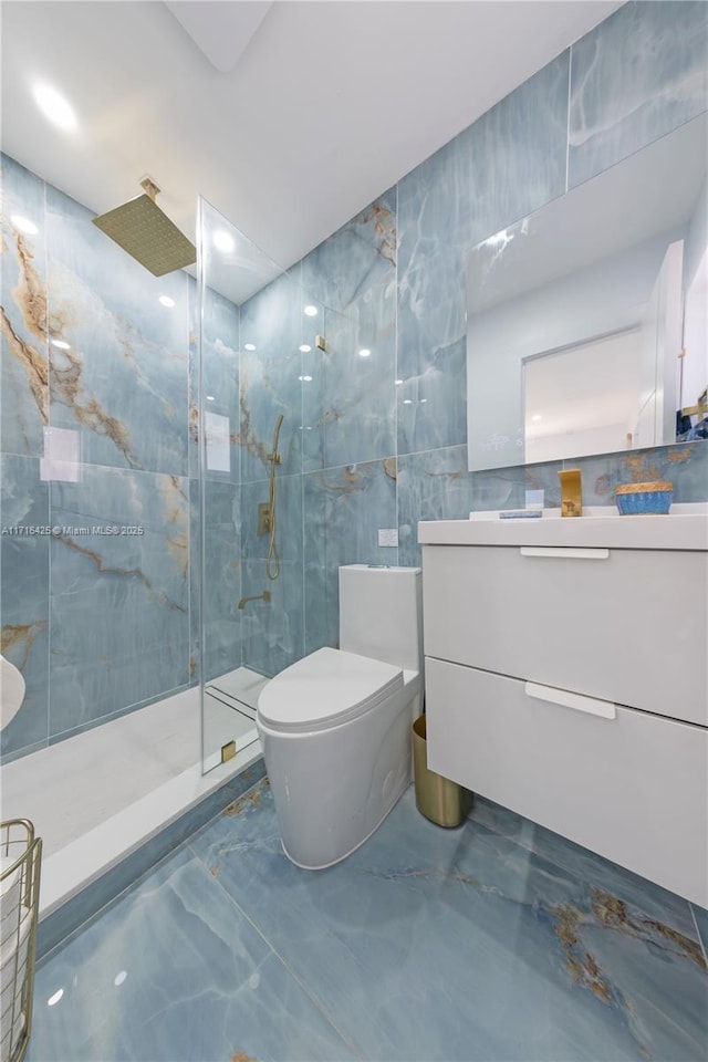 bathroom featuring tiled shower, vanity, toilet, and tile walls