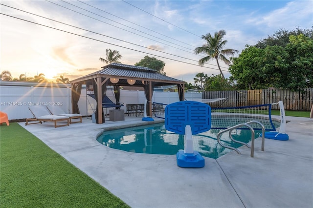 pool at dusk with a gazebo and a patio