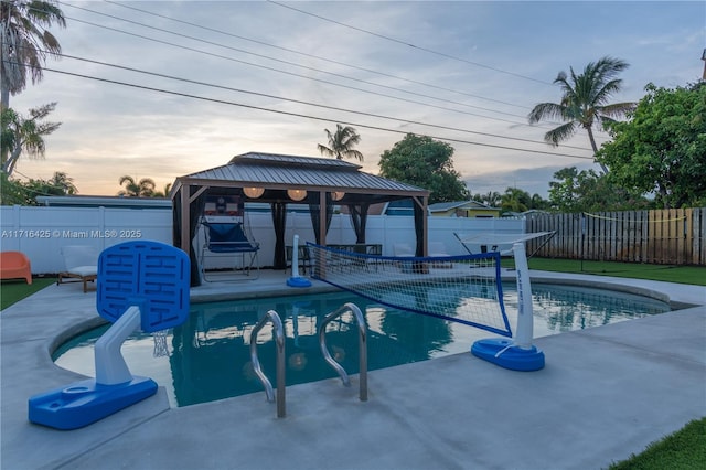 pool at dusk with a gazebo and a patio area