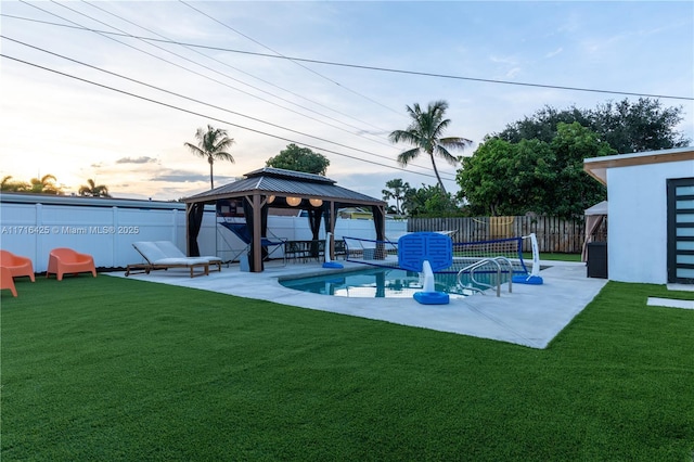 pool at dusk featuring a gazebo, a patio, and a lawn