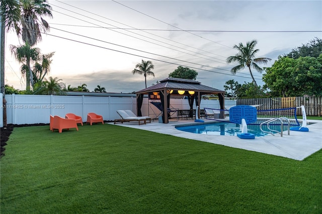 pool at dusk featuring a gazebo and a lawn