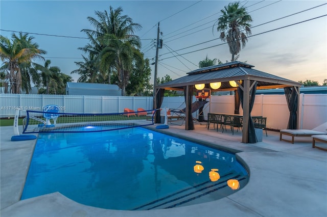 pool at dusk with a gazebo and a patio