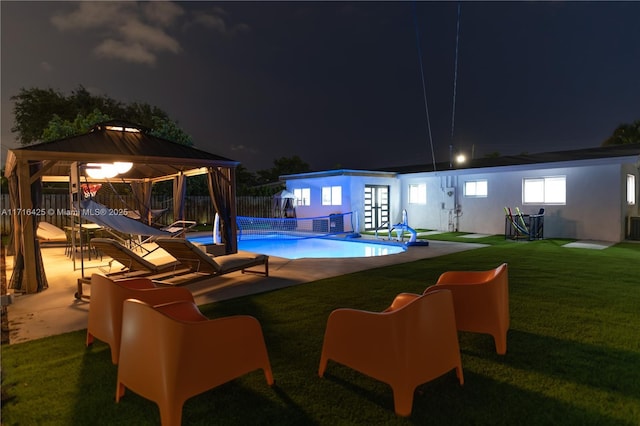 pool at twilight with a gazebo, a patio area, an outbuilding, and a yard