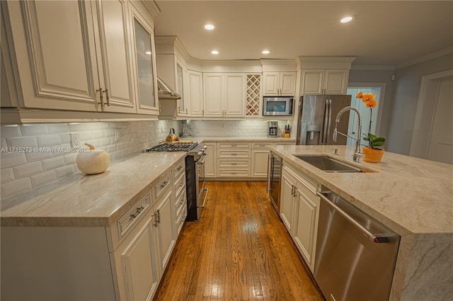 kitchen with backsplash, light stone counters, stainless steel appliances, white cabinetry, and an island with sink