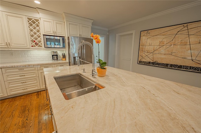 kitchen featuring appliances with stainless steel finishes, tasteful backsplash, light stone counters, ornamental molding, and sink