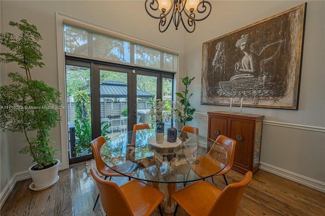 dining area with french doors, hardwood / wood-style flooring, and an inviting chandelier