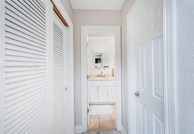 corridor featuring tile patterned floors, crown molding, and sink