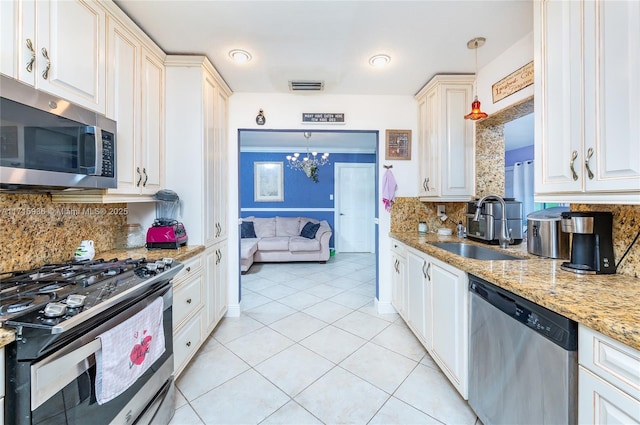 kitchen featuring decorative backsplash, stainless steel appliances, sink, decorative light fixtures, and a chandelier