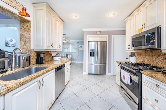 kitchen with backsplash, light stone counters, stainless steel appliances, crown molding, and sink