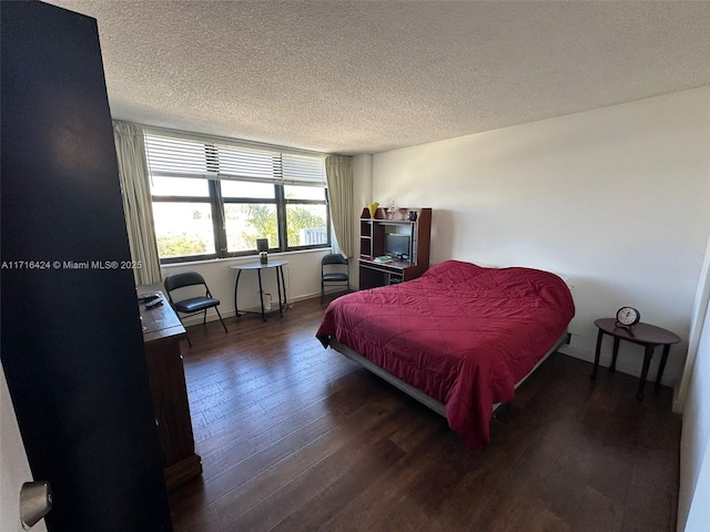 bedroom featuring a textured ceiling and dark hardwood / wood-style flooring