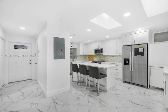 kitchen with white cabinetry, electric panel, a breakfast bar area, a kitchen island, and appliances with stainless steel finishes