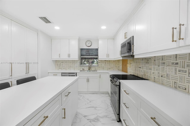 kitchen with tasteful backsplash, sink, white cabinets, and appliances with stainless steel finishes