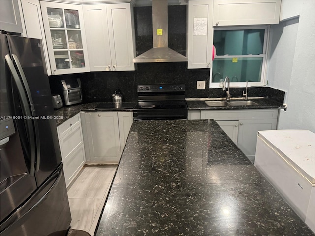 kitchen with electric range, stainless steel fridge, white cabinets, and wall chimney range hood