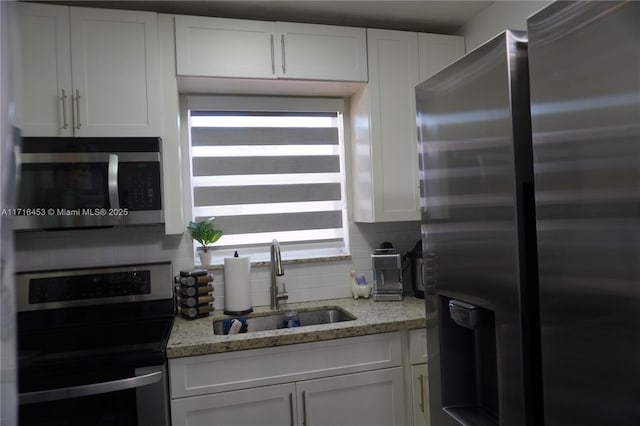 kitchen featuring appliances with stainless steel finishes, backsplash, white cabinetry, and sink