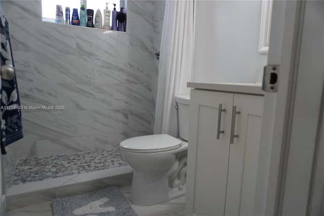 bathroom featuring vanity, toilet, and tiled shower