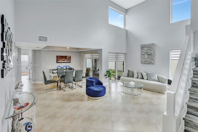 living room featuring visible vents, baseboards, a high ceiling, and tile patterned flooring