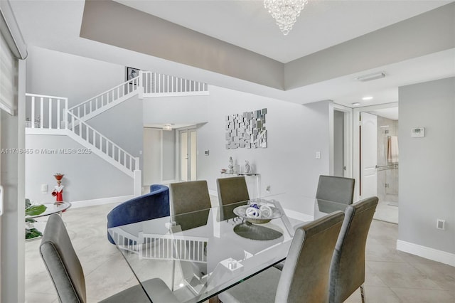 tiled dining space featuring an inviting chandelier, stairs, and baseboards