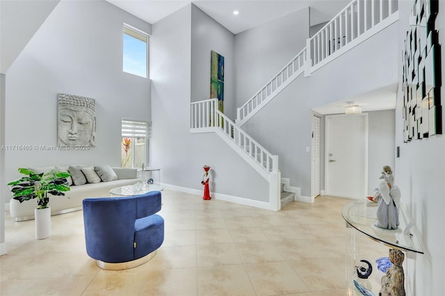 tiled living room with recessed lighting, baseboards, a towering ceiling, and stairs