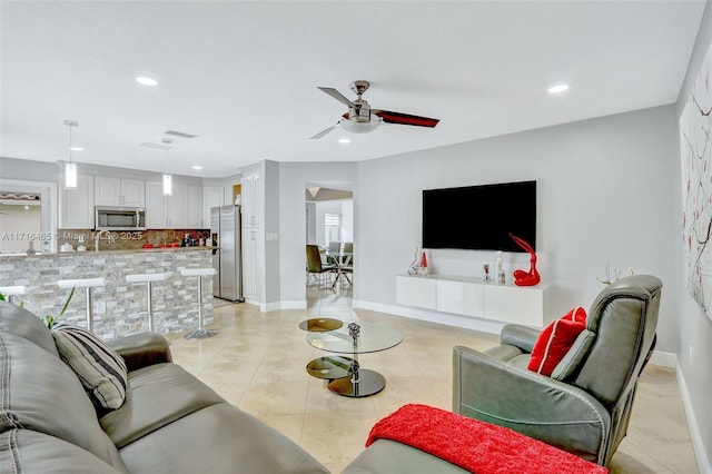 living area with light tile patterned floors, a ceiling fan, recessed lighting, and baseboards
