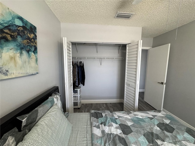 bedroom featuring dark hardwood / wood-style flooring, a closet, and a textured ceiling