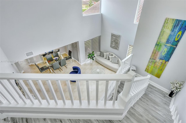 stairway with visible vents, baseboards, wood finished floors, and a towering ceiling