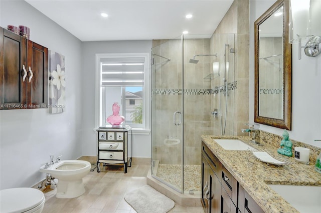 bathroom with a shower stall, toilet, a bidet, double vanity, and a sink