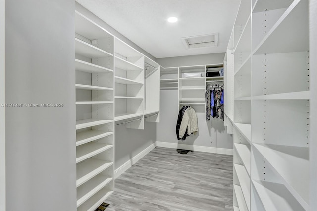 spacious closet with attic access and wood finished floors