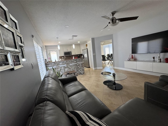 living room featuring light tile patterned floors, a textured ceiling, and ceiling fan