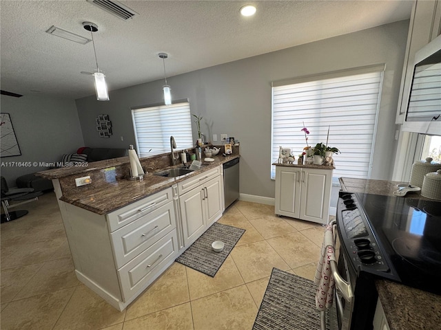 kitchen with stove, a textured ceiling, sink, white cabinets, and hanging light fixtures