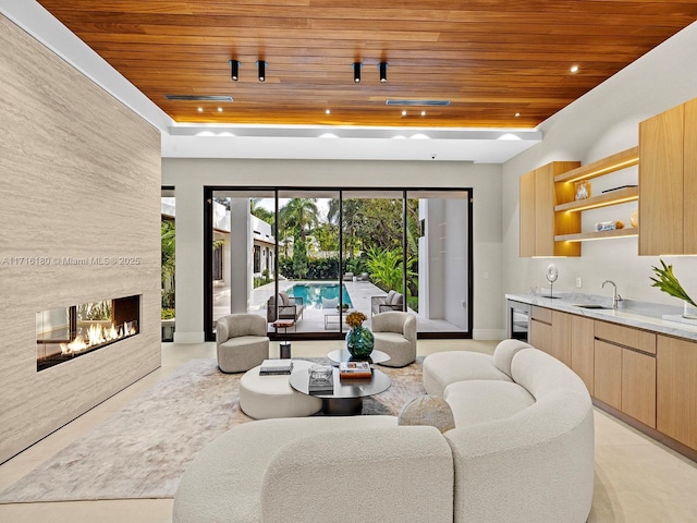 living room featuring wooden ceiling, wine cooler, a raised ceiling, and a multi sided fireplace