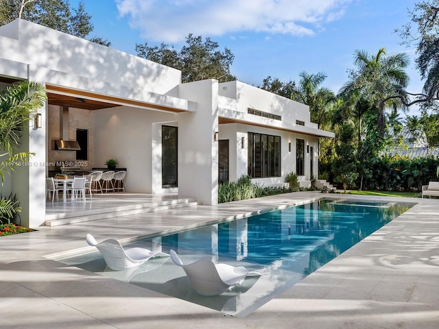 back of property featuring a patio area, outdoor dining area, an outdoor pool, and stucco siding