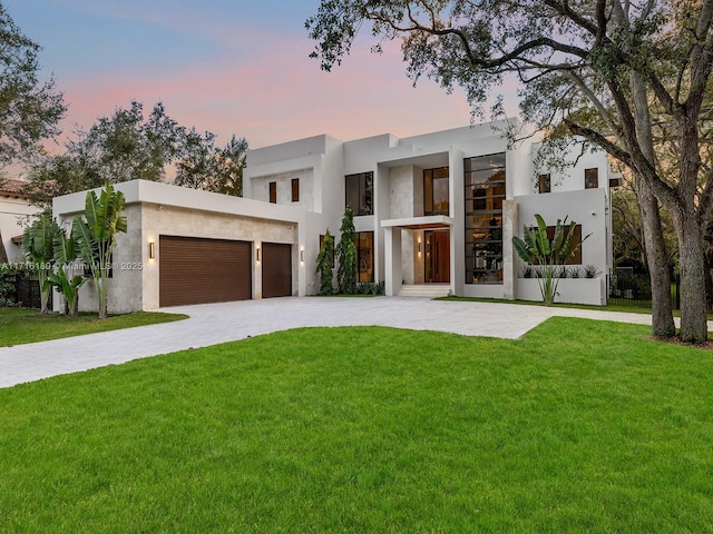 modern home with an attached garage, a lawn, decorative driveway, and stucco siding