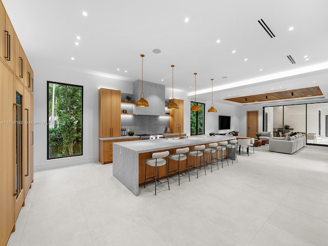 kitchen featuring backsplash, a breakfast bar, sink, a large island with sink, and hanging light fixtures