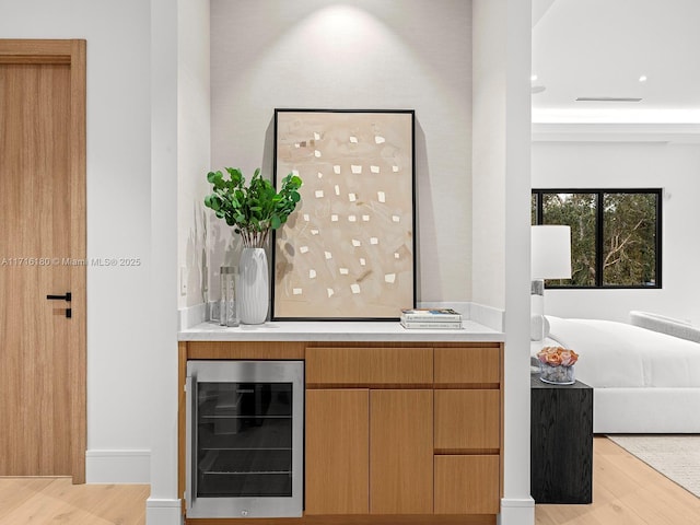 bar featuring beverage cooler and light hardwood / wood-style flooring