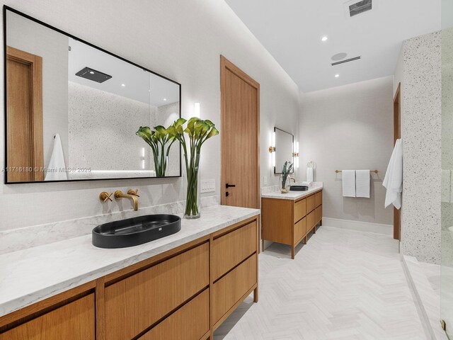 bathroom with visible vents, two vanities, a sink, and recessed lighting